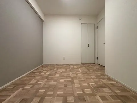 5帖の洋室。グレーの壁がアクセント。木目の床で落ち着きのある空間です。