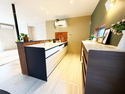 ブラウンタイル張りの対面式キッチン。リビングを見渡せて、背面に棚があるのでたっぷり収納◎