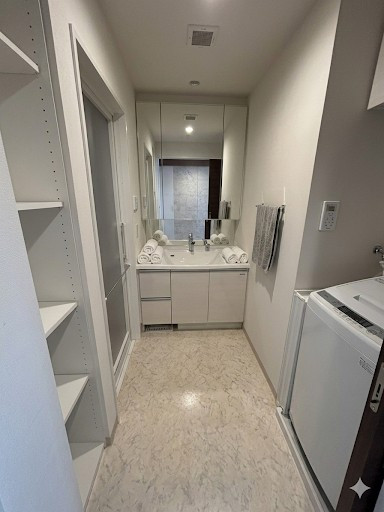 白を基調とした清潔感あふれる洗面空間。大きな三面鏡と広々としたカウンターが、忙しい朝の時間にゆとりをもたらします。※居住中のため、実際には家具小物等がございます。