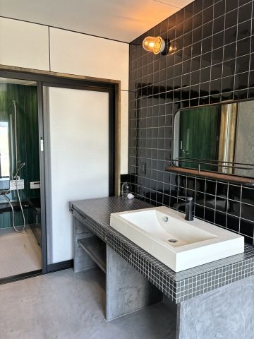 黒のタイルとホテルライクなワイドの洗面ボウルのスタイリッシュな造作洗面台。