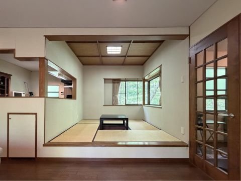 リビングの隣には、一段高くなった小上がりの和室が。掘りごたつで足を伸ばしてくつろいだり、ゲストの寝室にしたりと、多目的に使えます。窓外の緑が、空間に彩りを添えます。キッチンへの動線もスムーズ。